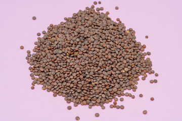 a pile of legumes, uncooked lentils on a pink background. cooking, food and healthy lifestyle concept