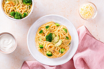 Broccoli and avocado pasta with grated cheese on stone background