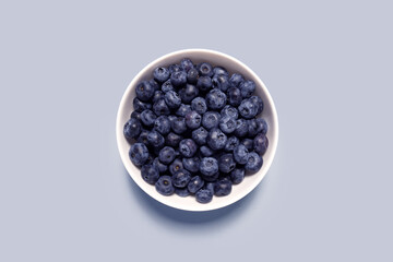Creative food health diet concept photo of plate dish bowl with blueberry on grey background..