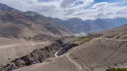 Landscape panorama of Pamir river gorge in high altitude desert bordering Afghanistan with Hindu Kush mountain range in background, Wakhan Corridor, Gorno-Badakshan, Tajikistan