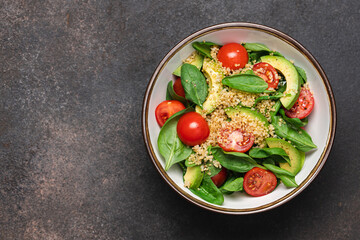 Spinach salad with quinoa and tomatoes. Healthy food bowl on dark background with copy space