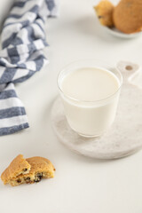 cookies and milk in a glass on a white table with a napkin