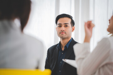 Asian business hold a small meeting inside the office or conference room. Brainstorm to exchange ideas. There are stock boards Laptops and tablets are communication tools. Unity teamwork concept.