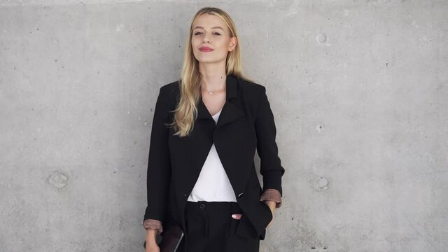 Self assured businesswoman near concrete wall