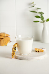 cookies and milk in a glass on a white table with little vase
