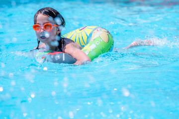 Beautiful young girl swimming in pool. Summer holiday, vacation  and happy childhood concept. Selective focus.