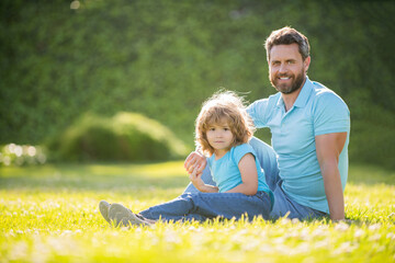 Naklejka na ściany i meble happy family portrait of father and son boy relax in summer park green grass, family love