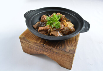 stir fried slices pork meat with fungus vegetables in hot clay pot in white background asian halal menu