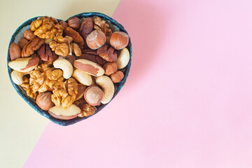 Assorted nuts in a plate in the form of a heart on a modern minimal background. Place for your text