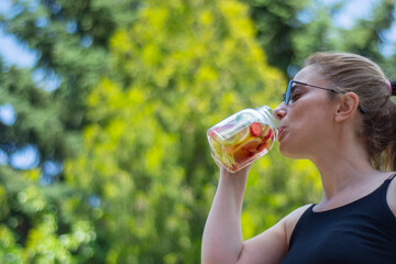 young woman enjoy detox drinks after doing pilates or yoga in their garden.