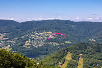 Paraglider pilot hovering over the Żar Mountain on a summer day