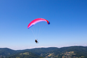 Fototapeta na wymiar Paraglider pilot hovering over the Żar Mountain on a summer day