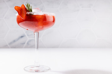 Fresh classic strawberry margarita cocktail with green rosemary twig, ice cube, fruit slices, sugar...