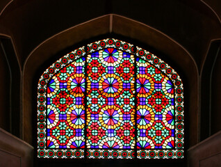 the colorful symmetric stained glass window of Iranian historic architecture