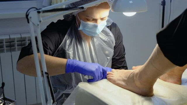 The podiatrist does a pedicure in the salon. Pedicure procedure with nail clipper tool