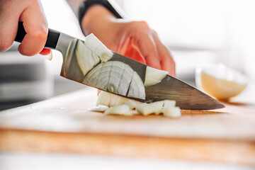 Chefs woman hands chopping onion on wooden board