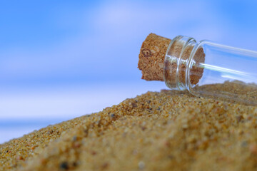 small glass jar with a cork lying on the sand