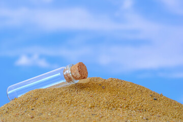 small glass jar with a cork lying on the sand