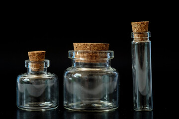 small glass jars with a cork on a black background
