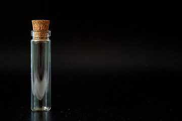 small glass jar with a cork on a black background