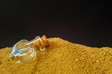small glass jar with a cork lying on the sand