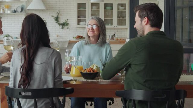 Happy multi-generation family toasting and smiling while having dinner together