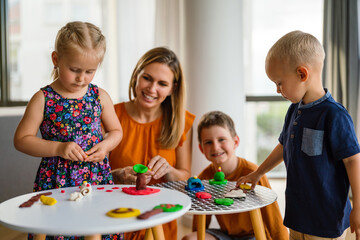 Kids playing with plasticine. Teacher or mother play with children. People, kid creativity concept