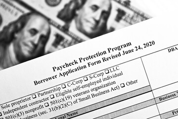 selective focus monochrome photo of paycheck protection program borrower application form revised, on a background of dollar bills