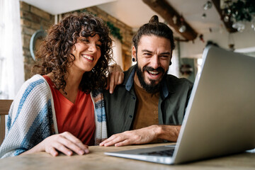 Couple relaxing together at home with computer pc having fun