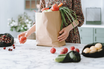Woman unpacking vegetables from paper grocery bag