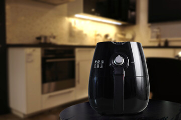 a black deep fryer or oil free fryer , air fryer appliance, is on black marble table in nice...