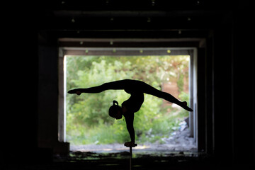 Fototapeta na wymiar Silhouette of flexible circus artist doing handstand. Concept of individuality, creativity and outstanding