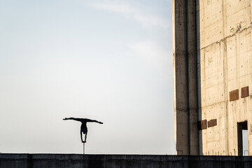 Silhouette of Circus artist doing handstand in urban style, copy space. Concept of individuality,...