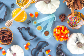 Halloween Gingerbread Cookies cooking background. Autumn holiday baking concept, ingredients, spices, halloween symbol cookie cutters - pumpkin, ghost, bat, witch hat, top view blue table copy space