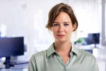 Attractive businesswoman looking at camera while standing at the office.