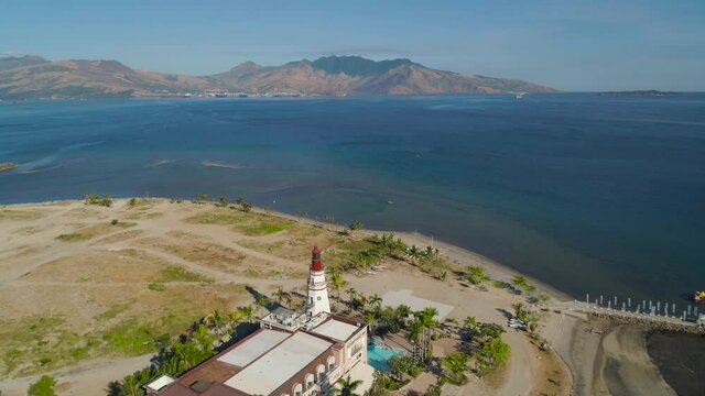 Coastal lighthouse in the sea bay. Lighthouse against mountains. Subic Bay, Philippines.