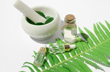 Essential oil made from natural ingredients. Bottles with essential oils, fern leaf and mortar with...