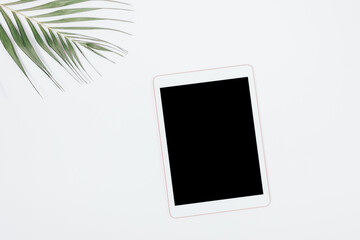 Tablet pc with blank screen next to palm leaf