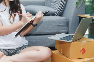 Fototapeta premium Successful entrepreneur business woman with online sales and Parcel shipping in her home office. Woman checking order on notebook.