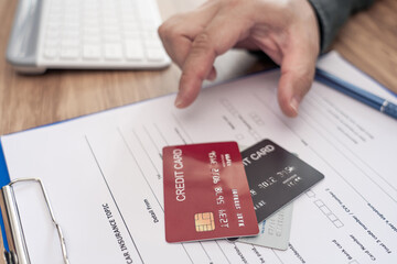 Close up credit cards on insurance document and hand a man for payment of Annual car insurance expenses that must be paid regularly instead of using cash
