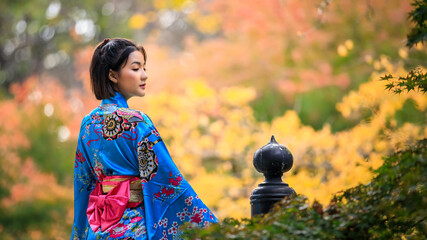 portrait of asian woman wearing japanese blue kimono in the park at autumn season in japan