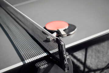 Abstract table tennis or ping pong texture. Monochrome colors with red accent color. Perspective view of  red and black rubberized wood paddles, black netting and table with heavy shadows.