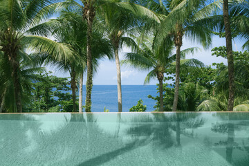 Fototapeta na wymiar View of nice infinity pool with clear blue water and tropic beach on back