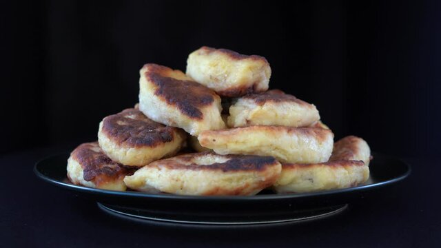 Potato cakes, ukrainian name potato zrazy, stuffed mushrooms or meat or cheese with herbs cream are fried in vegetable oil on black background, close up, rotates. Traditional Ukrainian cuisine