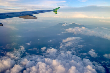 Fototapeta na wymiar view from a window plane, Merapi mountain and Merbabu mountain covered in clouds from a plane window.
