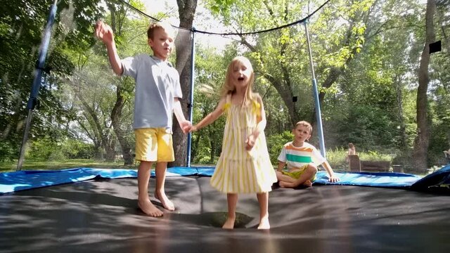 Happy kids have fun jumping on trampoline in the park