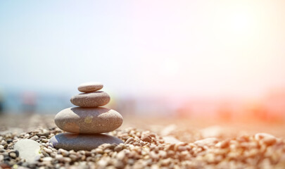 Fototapeta na wymiar Zen stones are background. A pyramid of pebble stones against the background of the sky, sea and beach. Meditation, yoga, calming the mind and relaxation concept.
