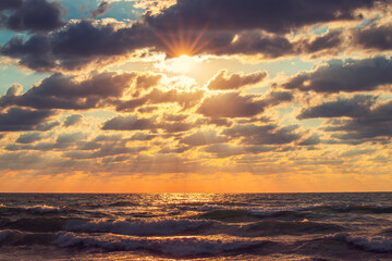 Beautiful sunrise over the sea waves and dramatic sky with clouds