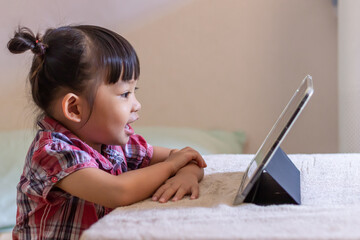 Portrait image of 3-4 years old preschool kid. Happy Asian child girl using and touching smart pad or tablet for do her homework and online learning (E-learning). Back to shool, Study frome home.