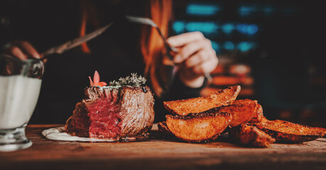woman hands with fork and knife eating beef steak in cafe